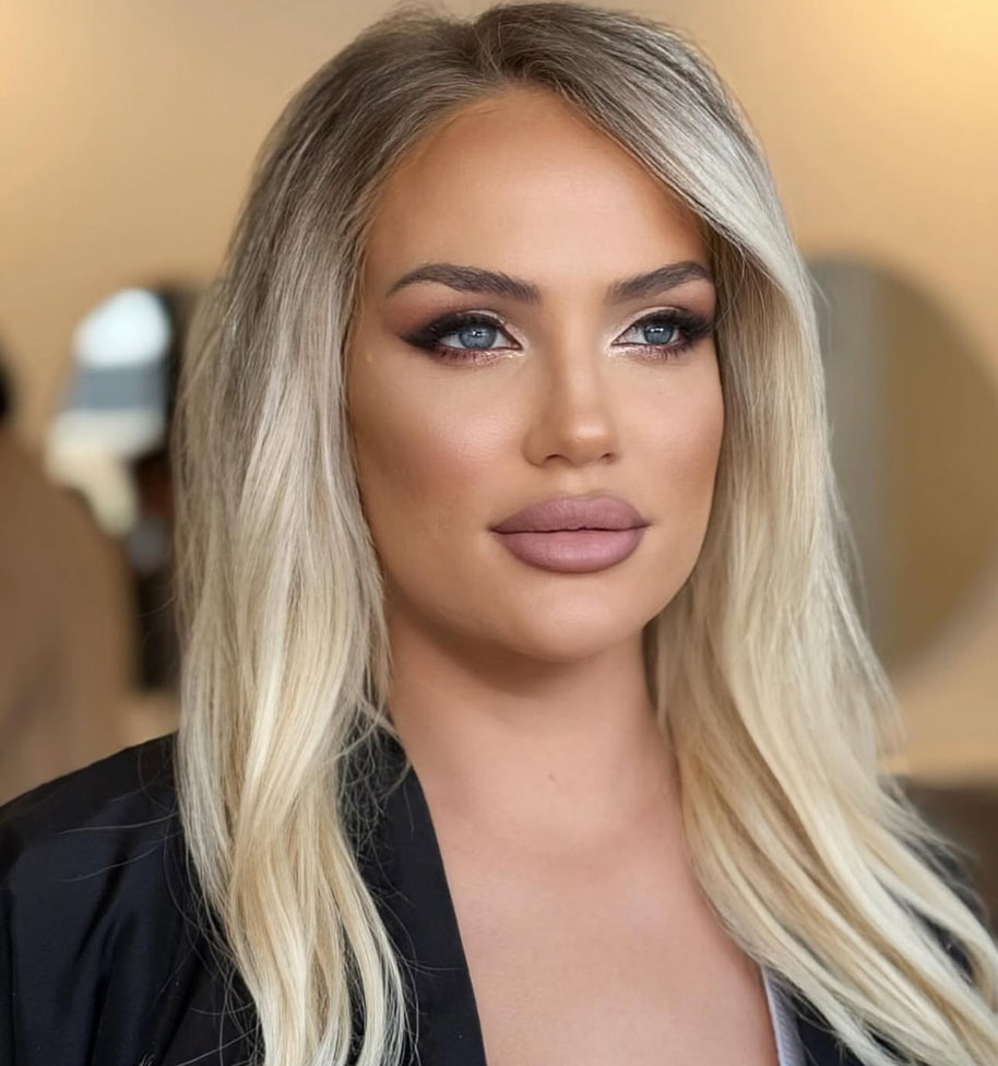 Woman with blonde hair and makeup against a blurred background
