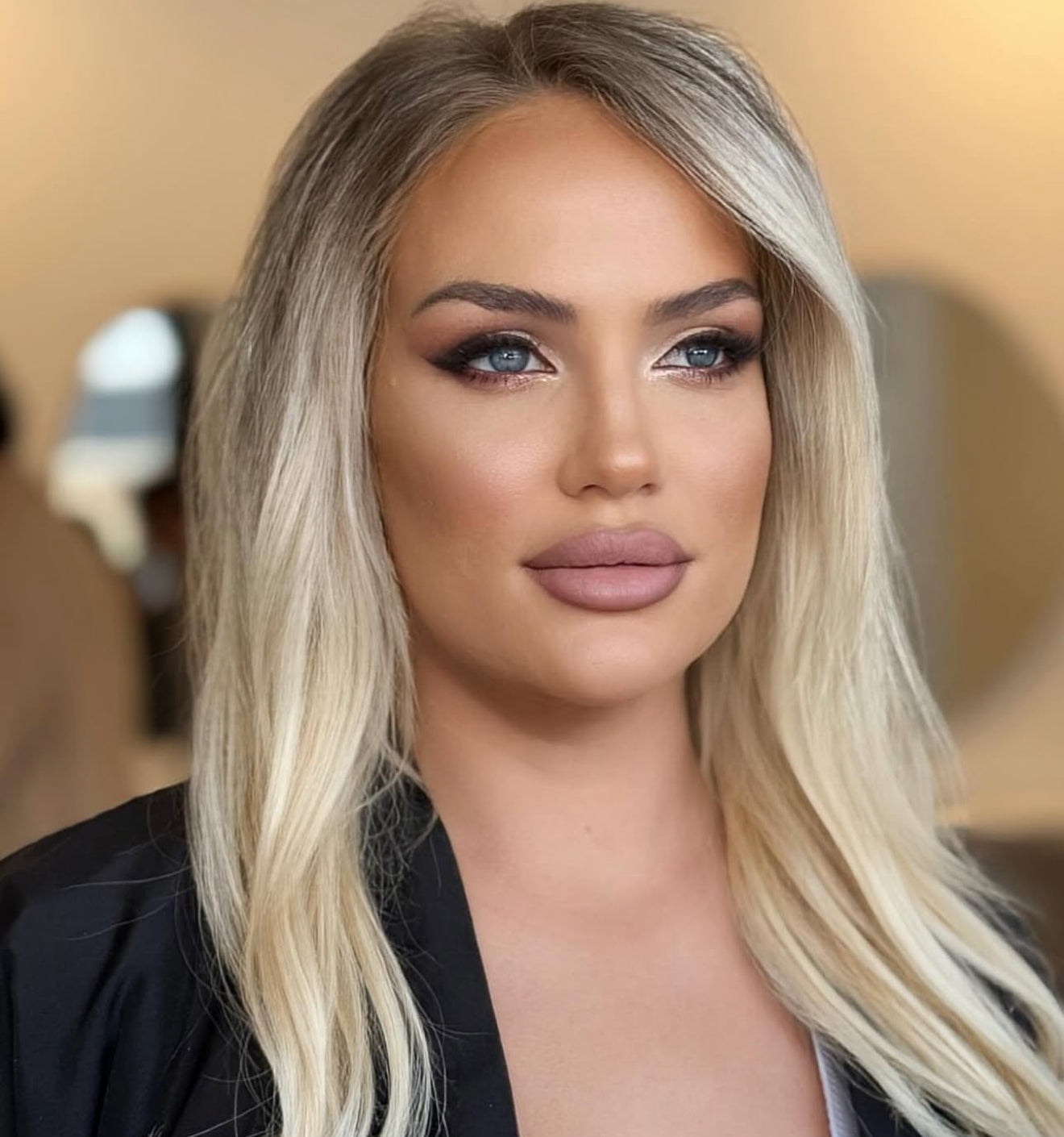 Woman with blonde hair and makeup against a blurred background