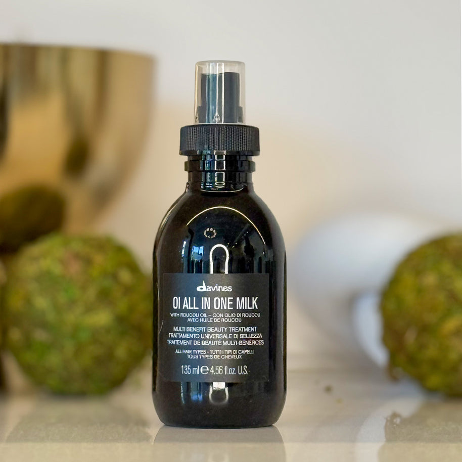 Black bottle of Davines Q1 All in One Milk on a neutral background