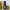 Black bottle of Davines OI Souffle hair product with green spherical objects in the background